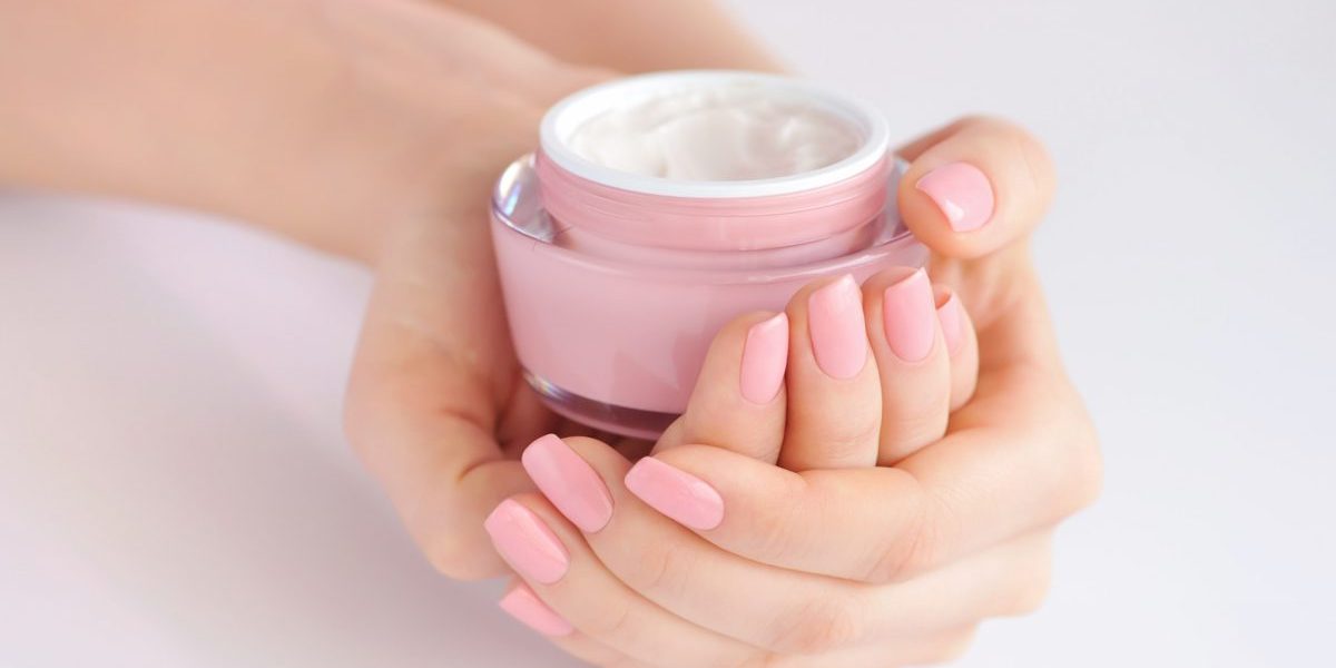 Hands of a woman with pink manicure with cream